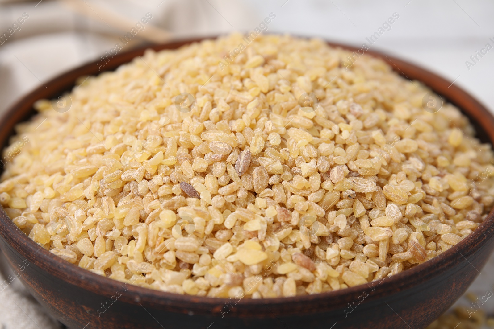 Photo of Raw bulgur in bowl on table, closeup