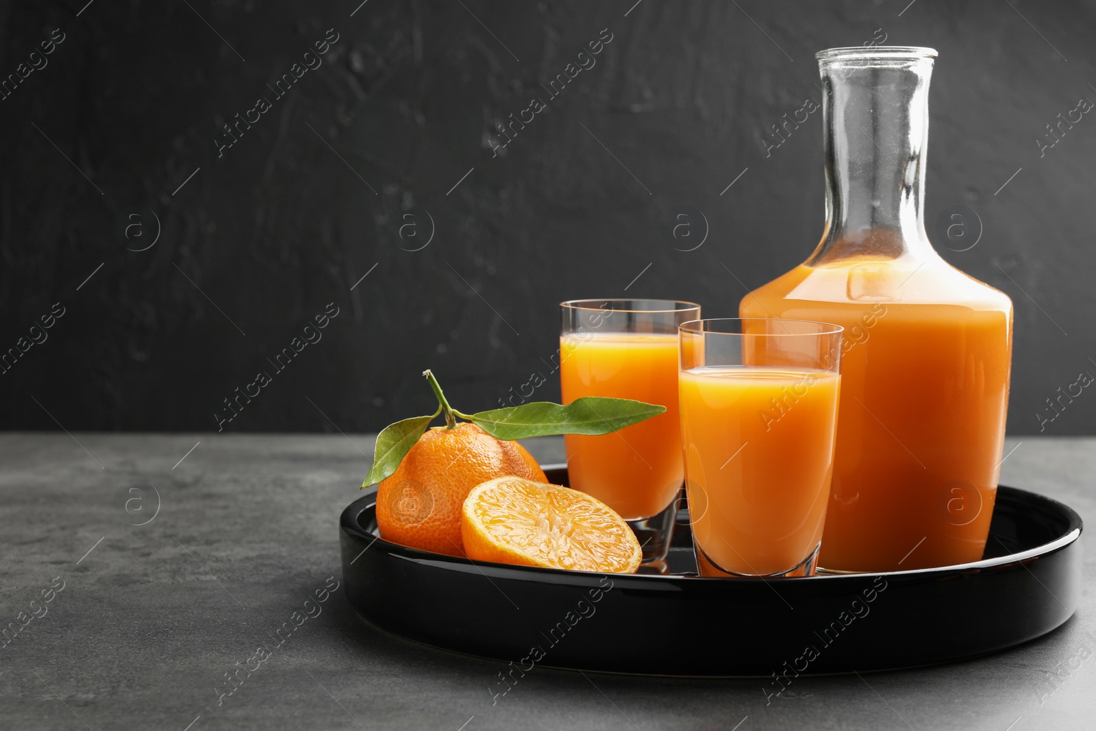 Photo of Delicious tangerine liqueur and fresh fruits on grey table, space for text