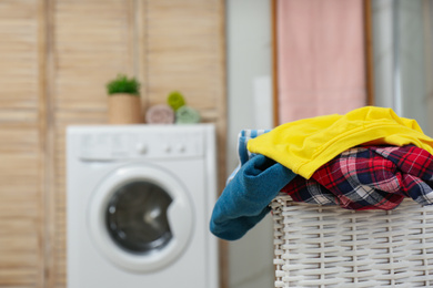 Photo of Wicker basket with laundry in bathroom. Space for text