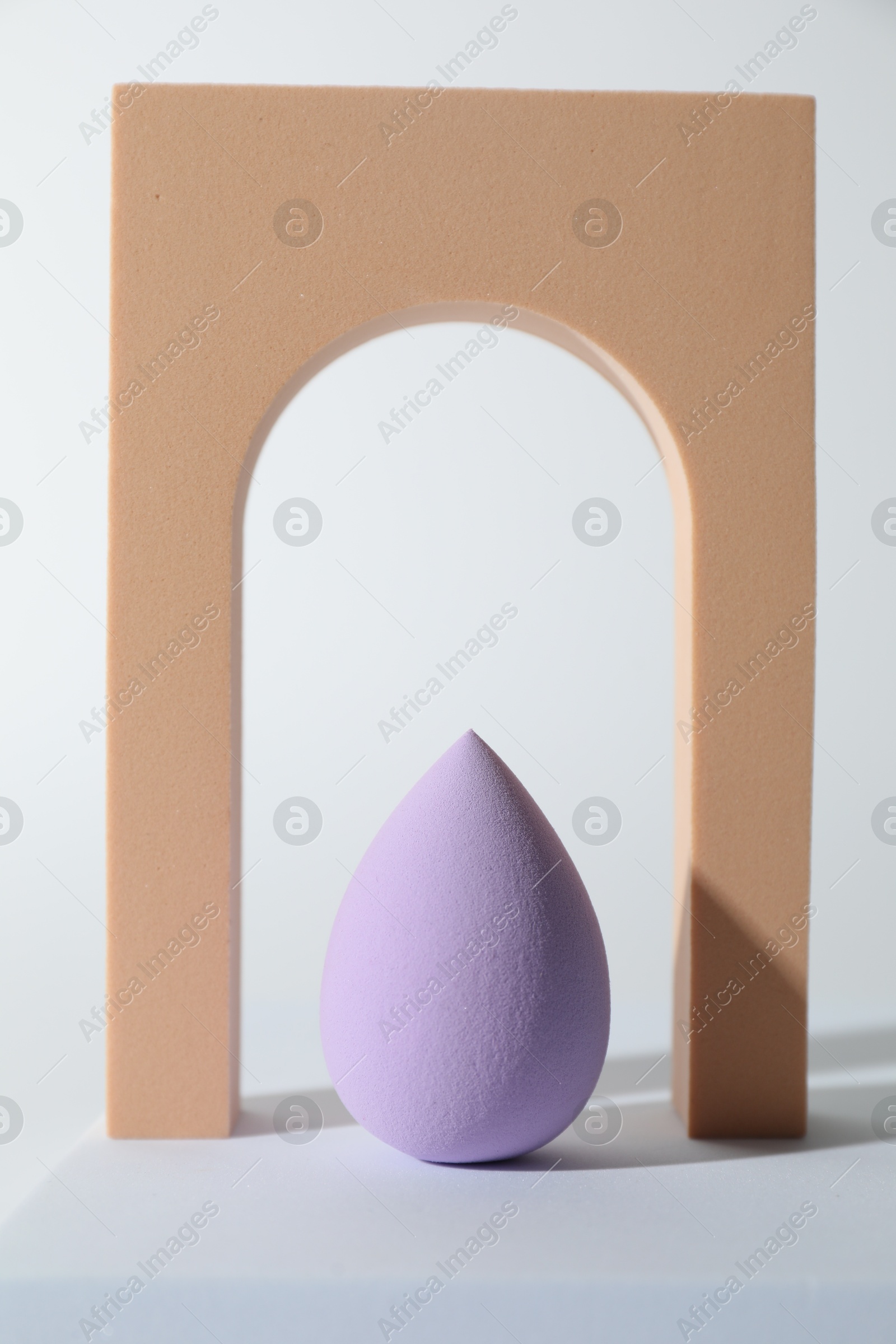 Photo of Stylish presentation of violet makeup sponge on white background