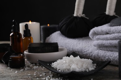 Photo of Spa composition. Sea salt, soap bar and towels on grey textured table, closeup