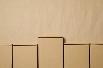 Many closed cardboard boxes on light brown background, flat lay. Space for text