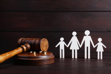 Divorce concept. Gavel, wedding rings and paper cutout of family on wooden table