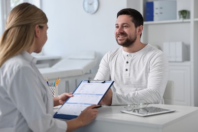 Photo of Professional doctor working with patient at white table in hospital