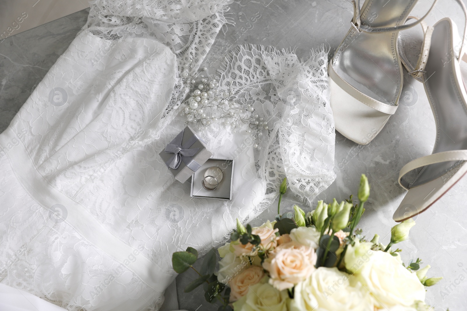 Photo of Flat lay composition with white wedding dress and engagement rings on grey marble table