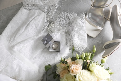 Photo of Flat lay composition with white wedding dress and engagement rings on grey marble table