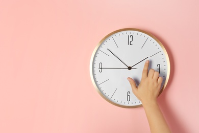 Woman touching clock on color wall, space for text. Time management