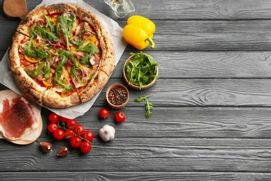Photo of Tasty pizza with meat and arugula on grey wooden table, flat lay. Space for text
