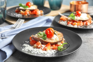 Photo of Baked eggplant with tomatoes, cheese and basil served on table