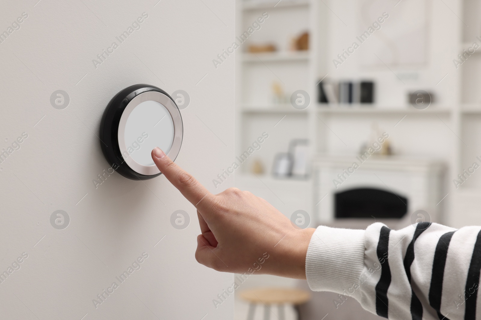 Photo of Woman adjusting thermostat on white wall indoors, closeup. Smart home system