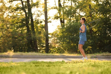 Young man training with jump rope in park