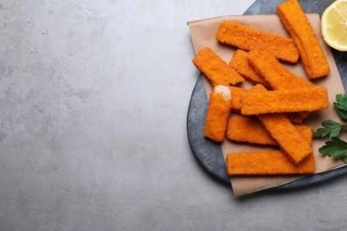 Photo of Fresh breaded fish fingers served on grey table, top view. Space for text