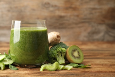 Photo of Green juice and fresh ingredients on wooden table. Space for text