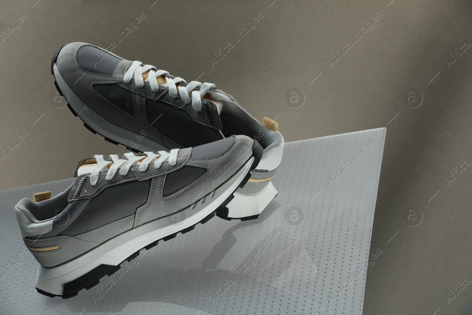 Photo of Stylish presentation of trendy sneakers against grey background, space for text