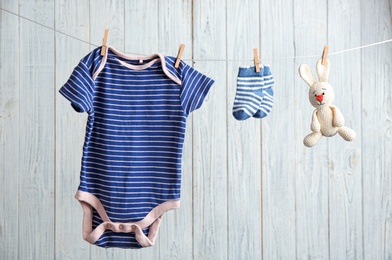 Baby accessories on laundry line against wooden background