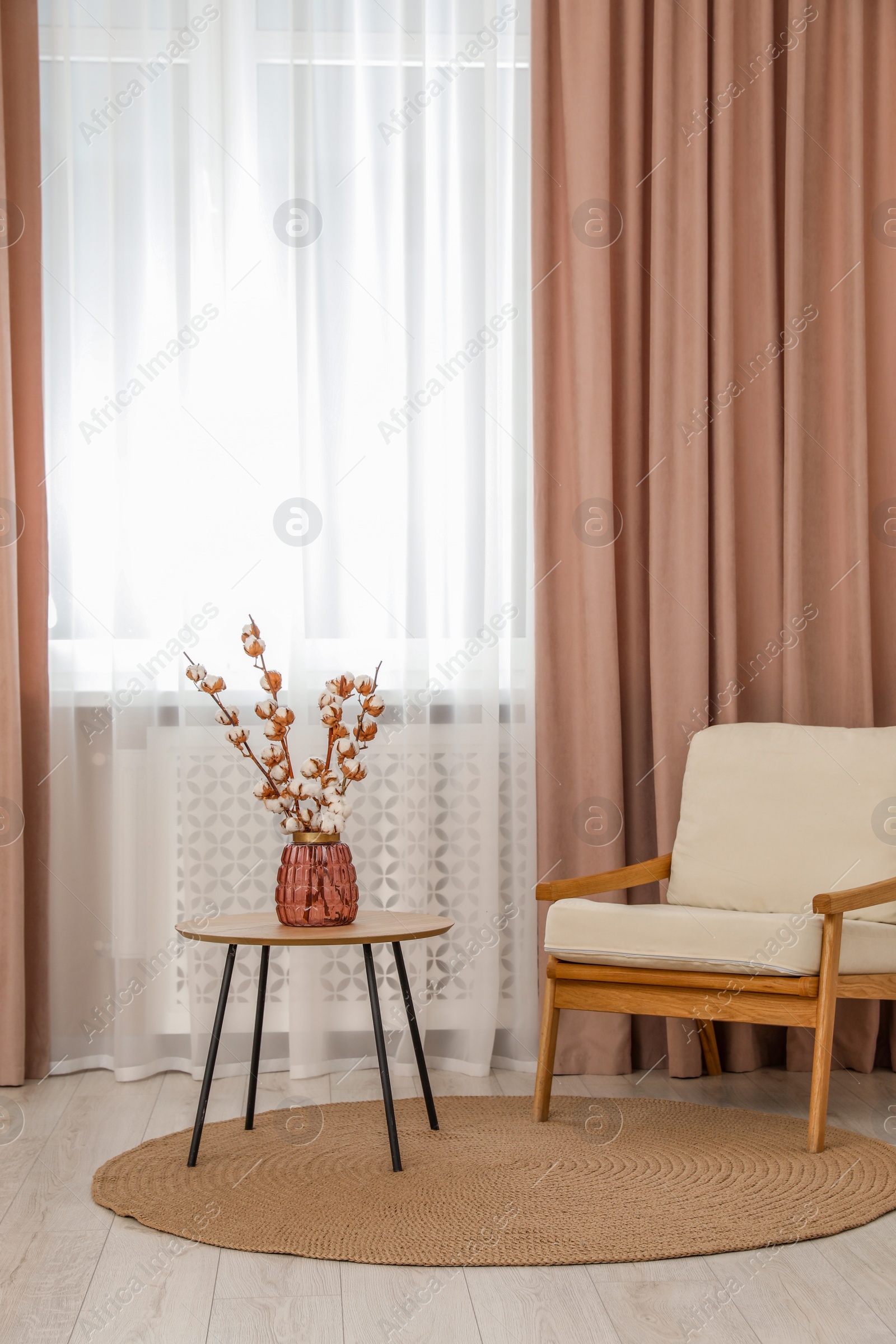 Photo of Living room with pastel window curtains, wooden table and armchair