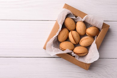 Delicious nut shaped cookies with boiled condensed milk in box on white wooden table, top view