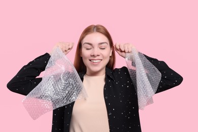 Woman holding bubble wraps on pink background. Stress relief