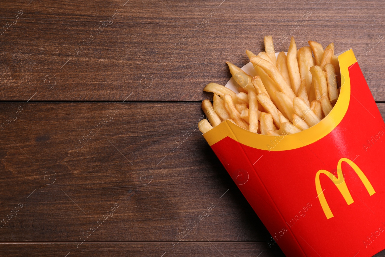 Photo of MYKOLAIV, UKRAINE - AUGUST 12, 2021: Big portion of McDonald's French fries on wooden table, top view. Space for text