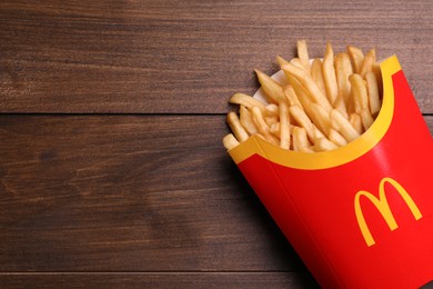 Photo of MYKOLAIV, UKRAINE - AUGUST 12, 2021: Big portion of McDonald's French fries on wooden table, top view. Space for text