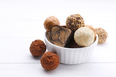 Tasty chocolate candies on white wooden table