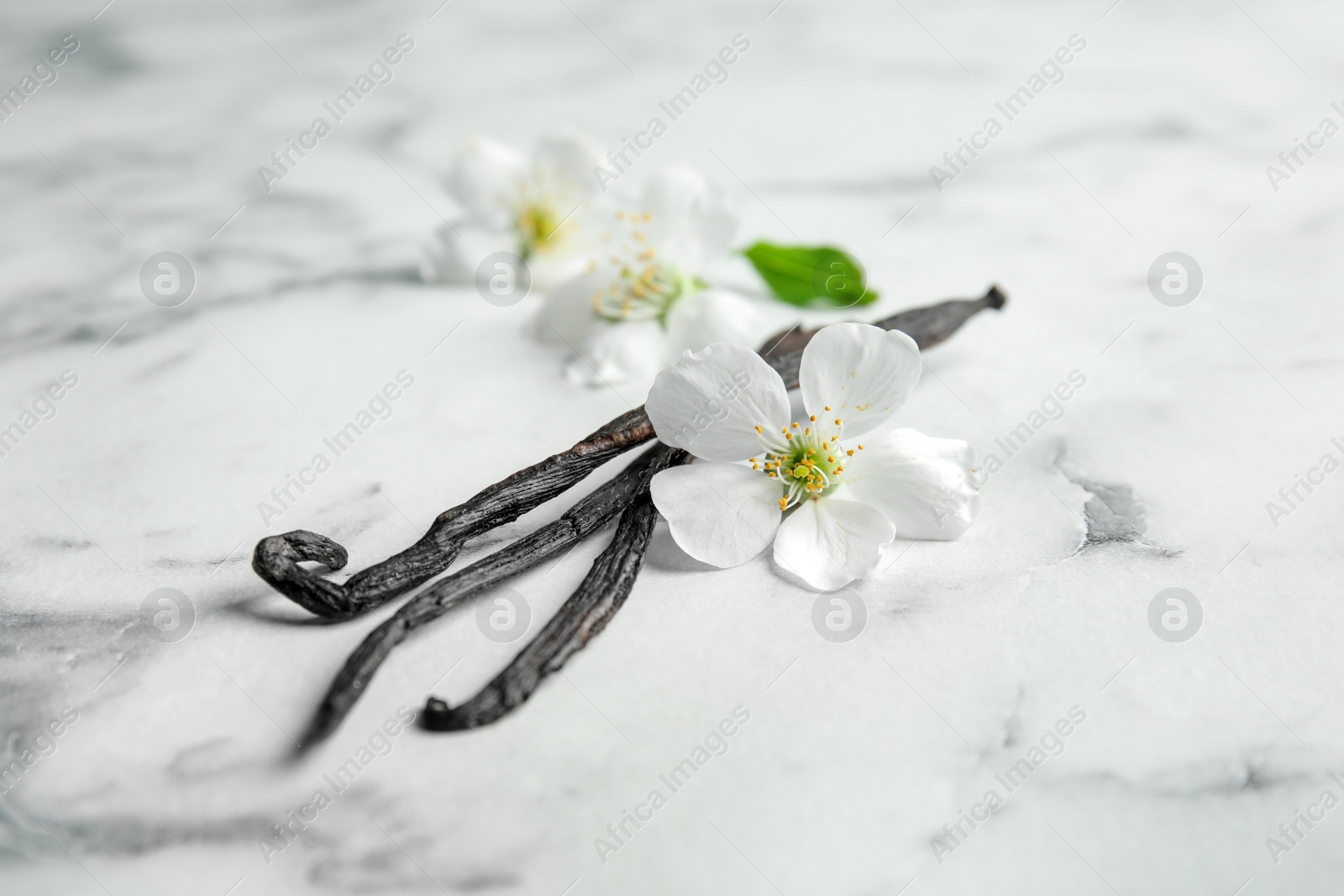 Photo of Aromatic vanilla sticks and flowers on marble background