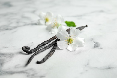 Photo of Aromatic vanilla sticks and flowers on marble background