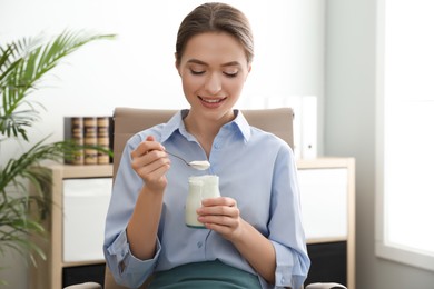 Photo of Young attractive woman with tasty yogurt in office