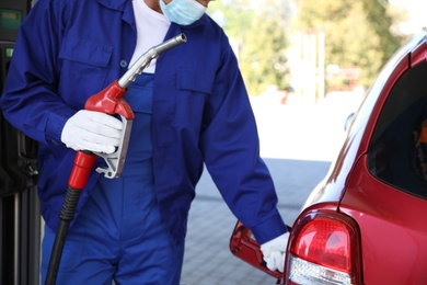 Worker refueling car at modern gas station, closeup