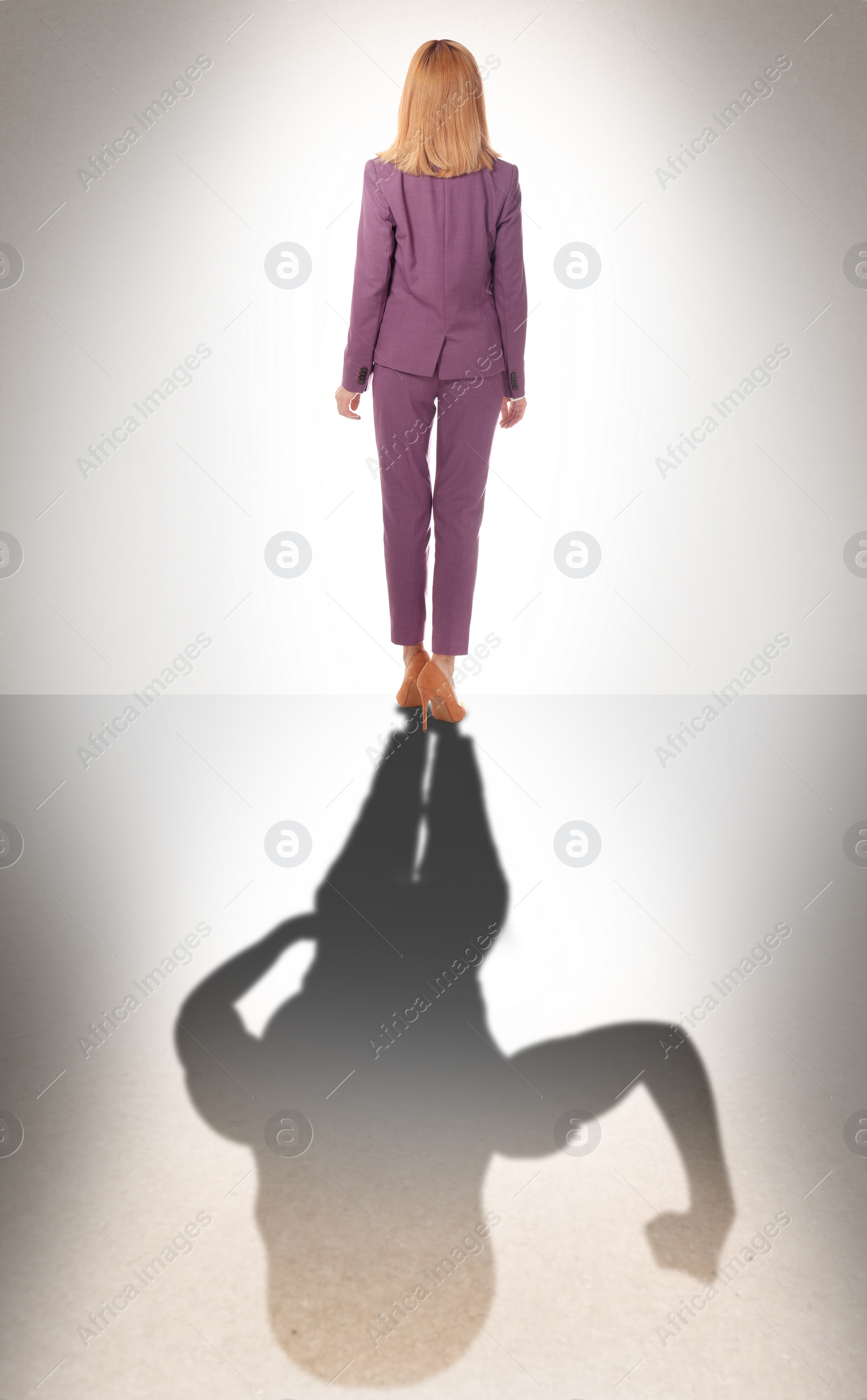 Image of Businesswoman and shadow of strong muscular lady behind her on light background. Concept of inner strength