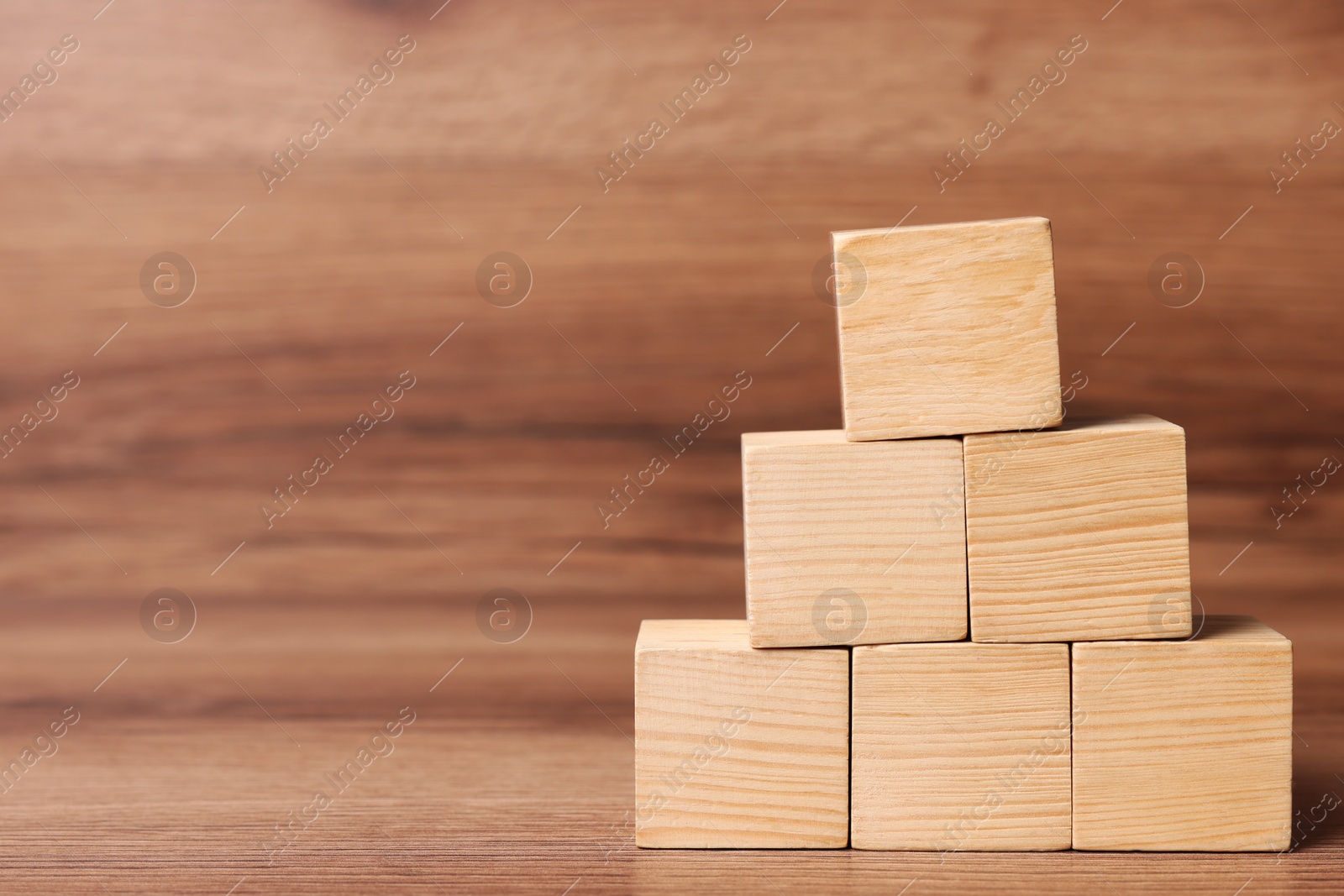 Photo of Pyramid of cubes on wooden background, space for text. Idea concept