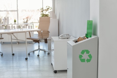 Photo of Open full trash bin in modern office, space for text. Waste recycling