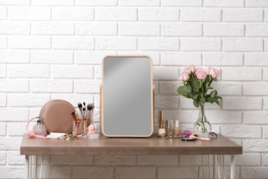 Photo of Dressing table with different makeup products and accessories in room interior