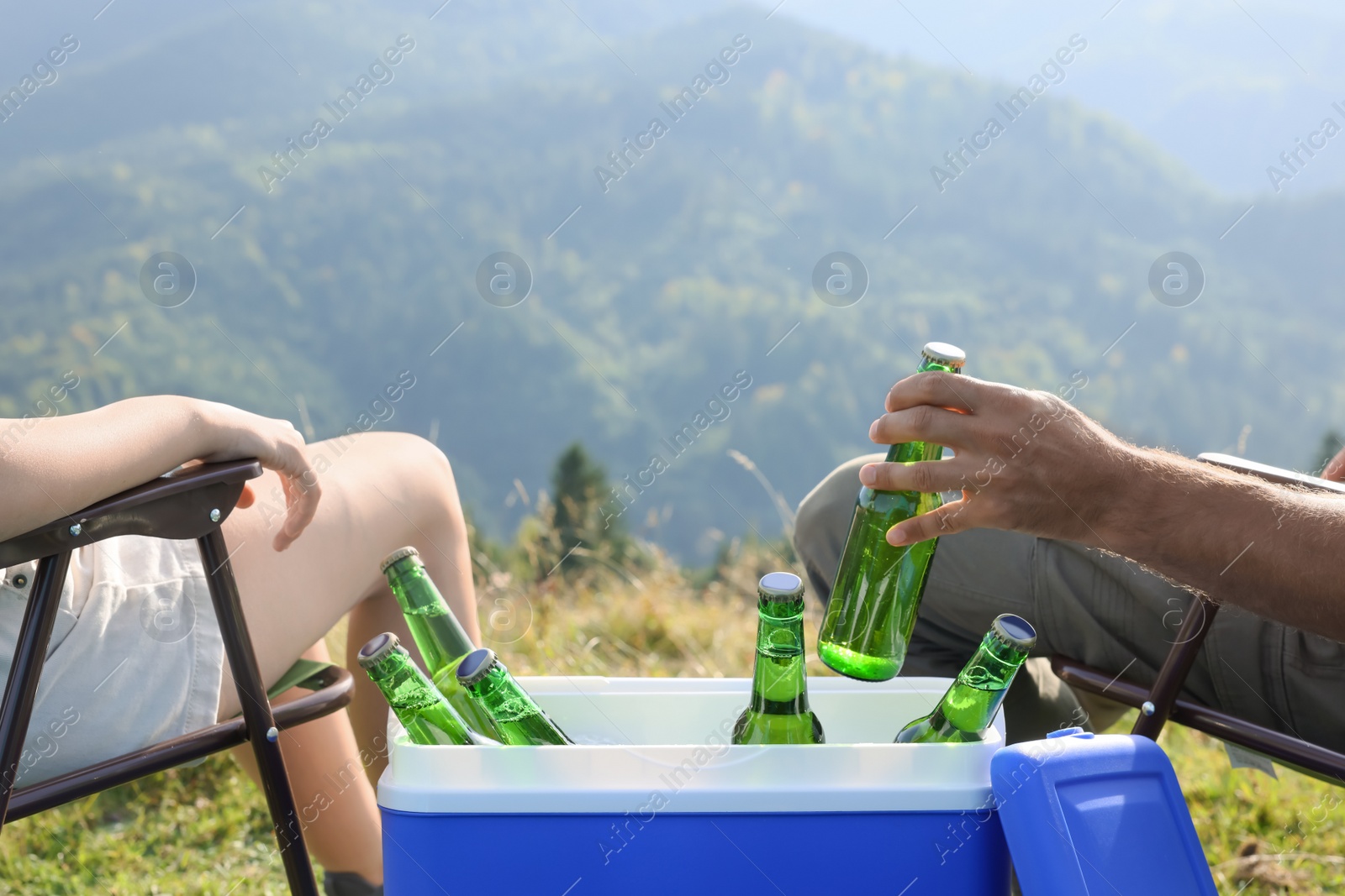 Photo of Couple and cool box with bottles of beer in nature, closeup