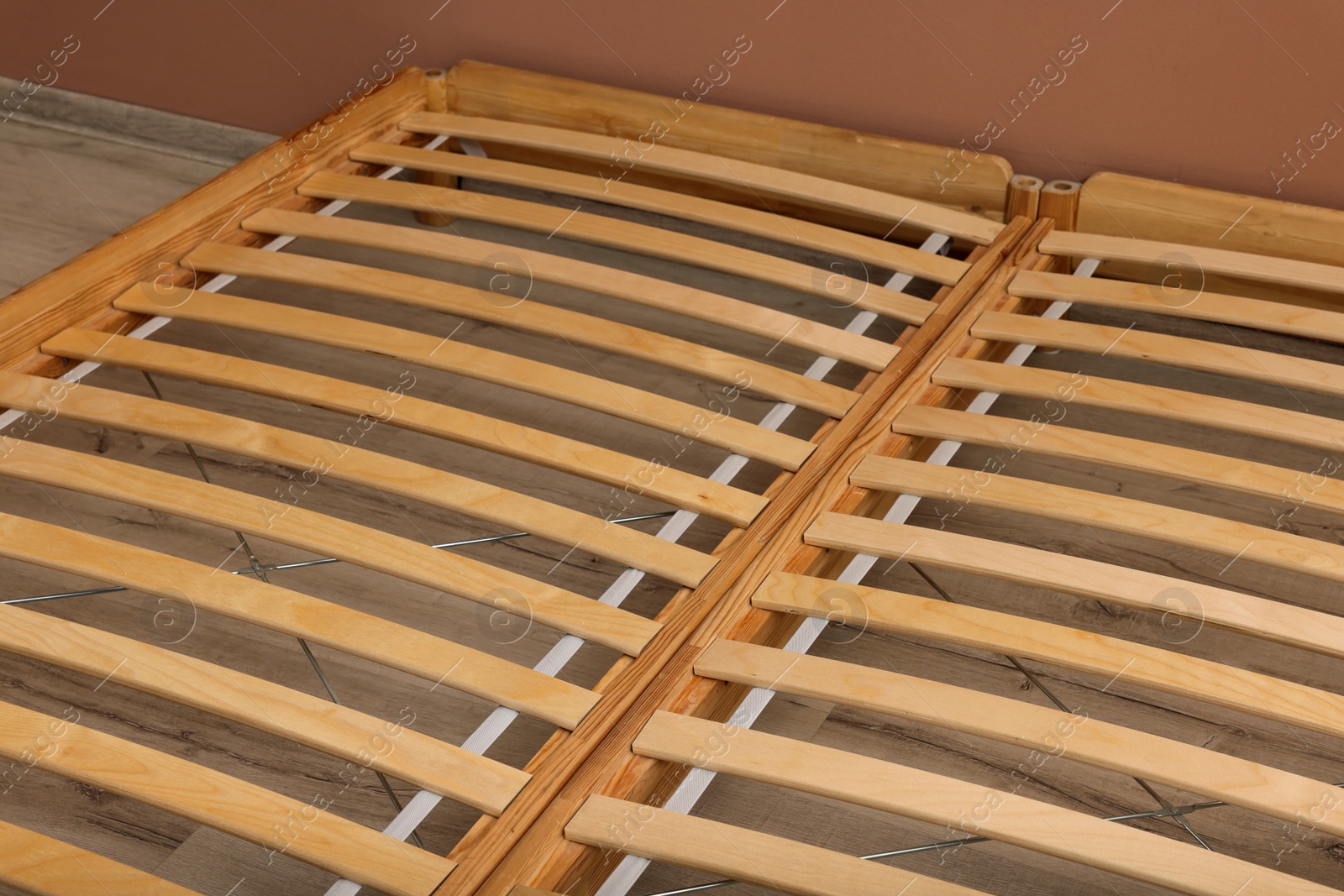 Photo of Wooden bed frame on floor indoors, closeup view