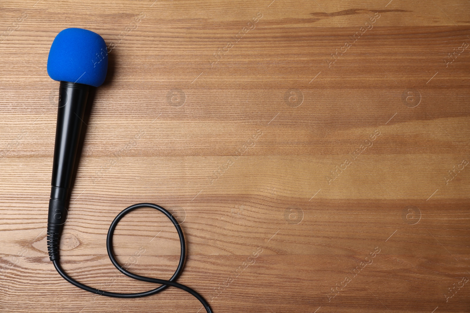 Photo of Modern microphone on wooden background, top view with space for text