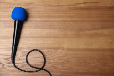 Photo of Modern microphone on wooden background, top view with space for text