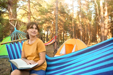 Photo of Woman with book resting in comfortable hammock outdoors