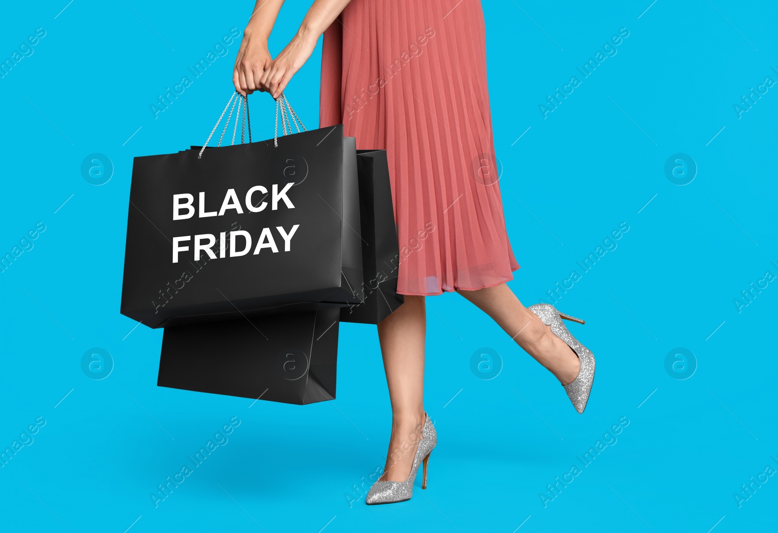 Photo of Woman with shopping bags on light blue background, closeup. Black Friday