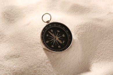 Photo of One compass on beach sand. Navigation equipment