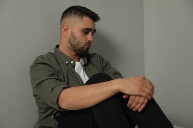 Photo of Portrait of sad man near light grey wall