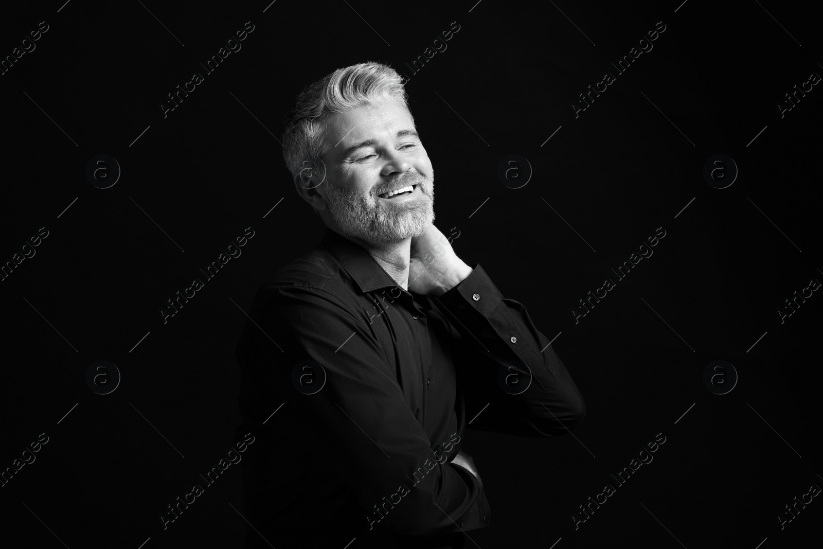 Photo of Portrait of smiling man on dark background. Black and white effect