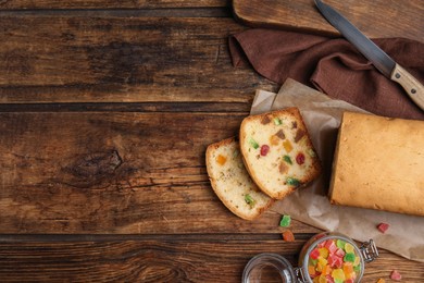 Photo of Delicious cake with candied fruits on wooden table, flat lay. Space for text