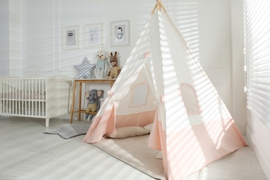 Comfortable crib and play tent in baby room. Interior design