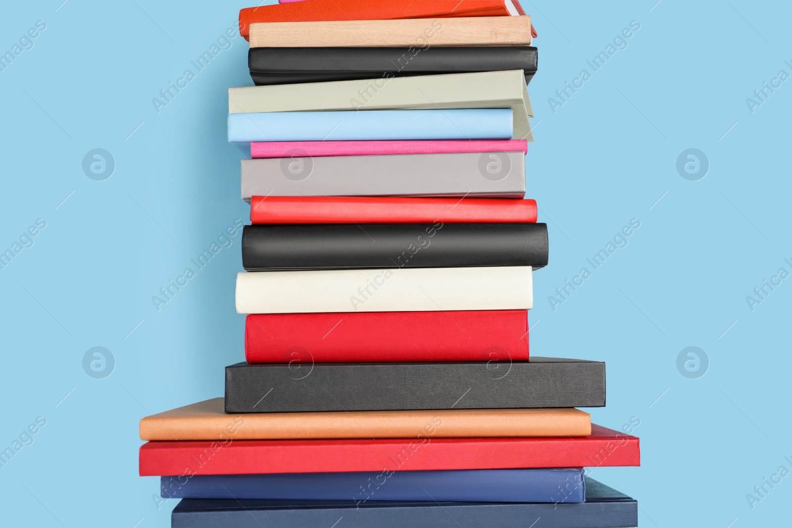 Photo of Stack of different books on light blue background