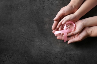 Photo of Woman and girl holding pink ribbon on grey background, top view with space for text. Breast cancer awareness