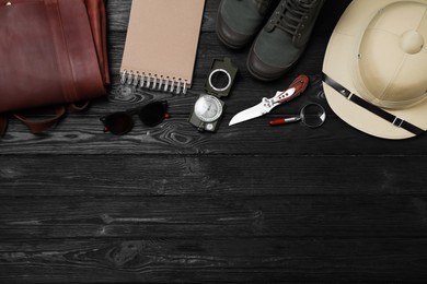 Flat lay composition with safari accessories on black wooden background, space for text