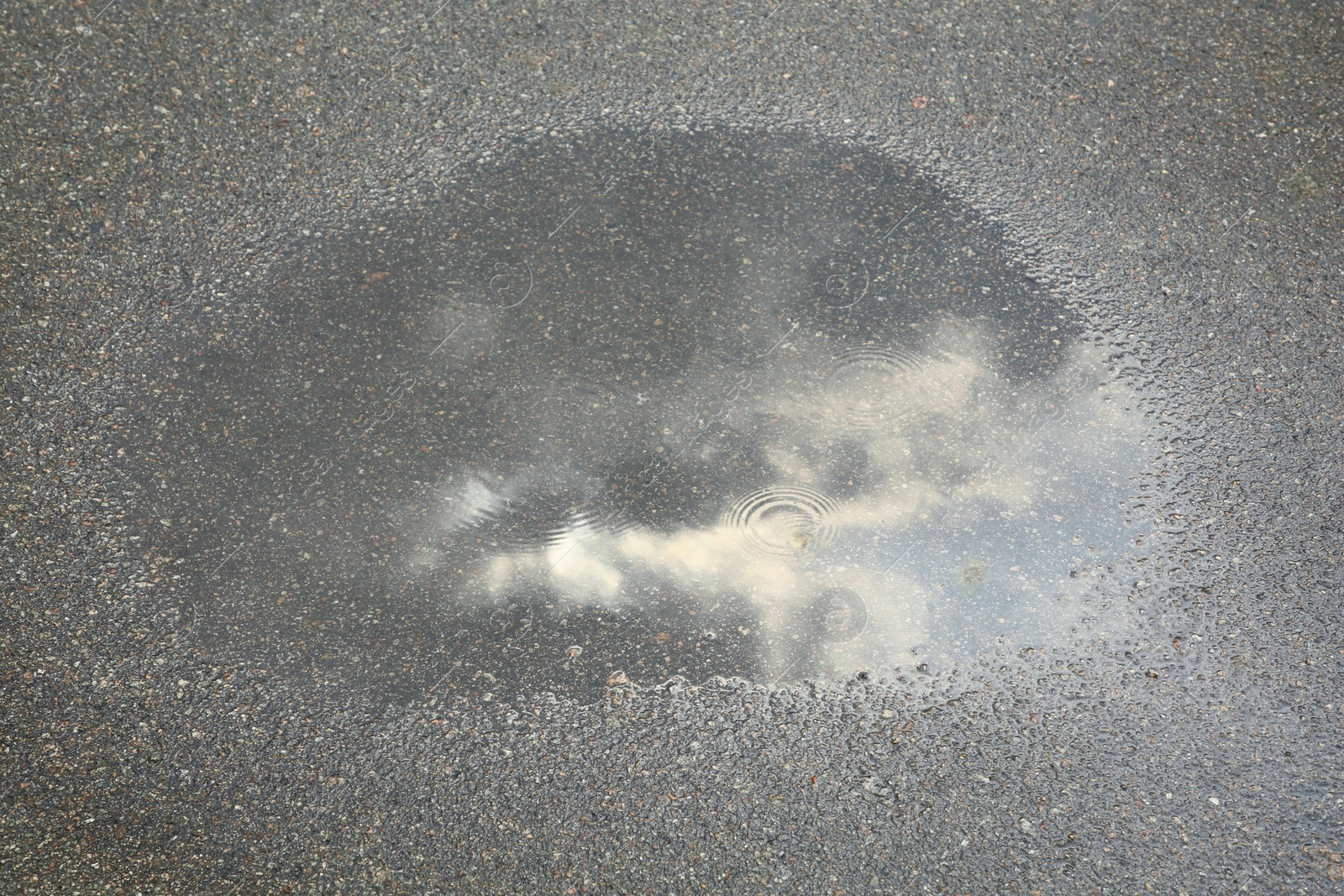 Photo of View of puddle on asphalt outdoors. Rainy day