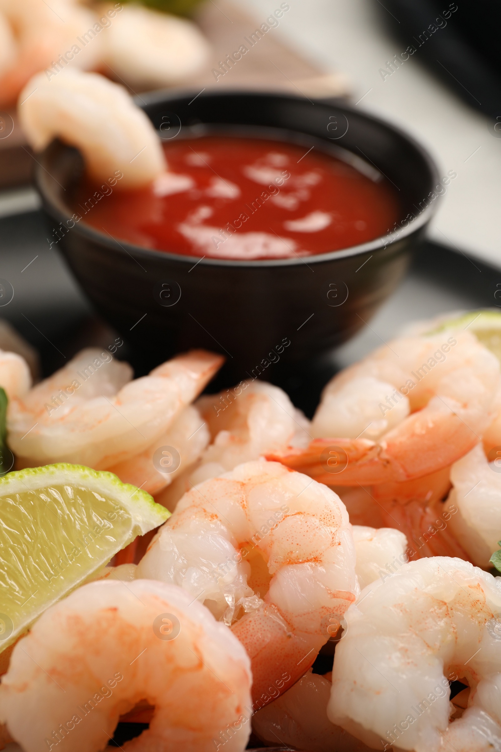 Photo of Tasty boiled shrimps with cocktail sauce, parsley and lime on table, closeup