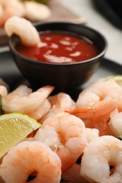 Tasty boiled shrimps with cocktail sauce, parsley and lime on table, closeup